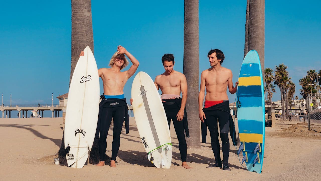 Three surfers standing on a beach with surfboards